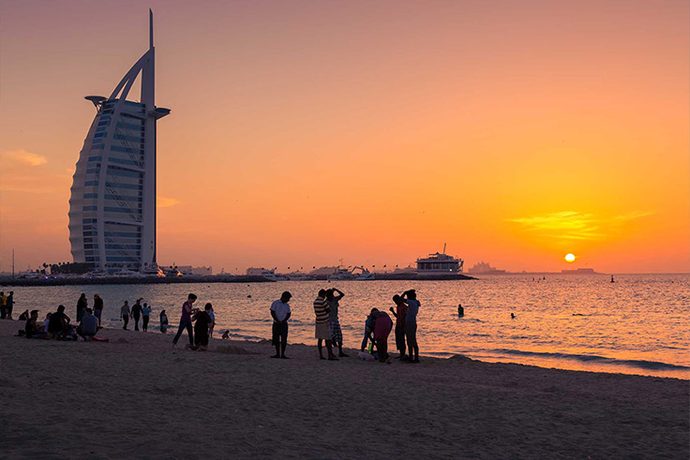 The Burj Al Arab at sunset, with people on the beach